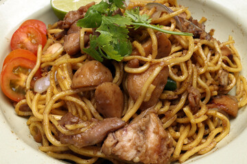 Stair fried yellow noodle traditional mee gorng tomato parsley lime on enamel metal plate