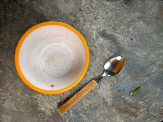 Empty bowl and spoon on cement floor background 