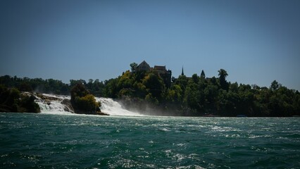 Fototapeta premium Aerial view of waterfall flowing from rocks surrounded by dense trees