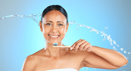 Dental, health and woman brushing teeth with toothbrush, toothpaste and water splash on blue studio...