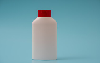 White plastic bottle with a green cap on a blue background