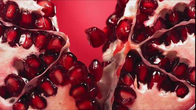 Pomegranate Splits in half and Grains rolls down with juise splash in slow motion