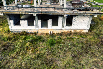 Abandoned construction site of a reinforced concrete monolithic house. Abandoned building materials. Stop financing construction. Shooting from a drone.
