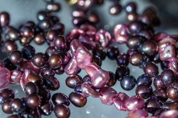 Macro abstract texture background of a necklace containing deep pink color baroque pearls with natural imperfections, on a translucent glass surface