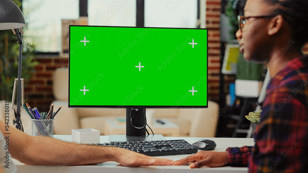 Poster multiethnic team working on computer with greenscreen at home, using monitor to examine isolated dis