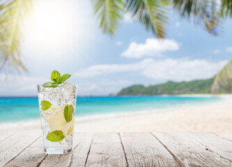 Mojito cocktail on wooden table in front of sunny sea