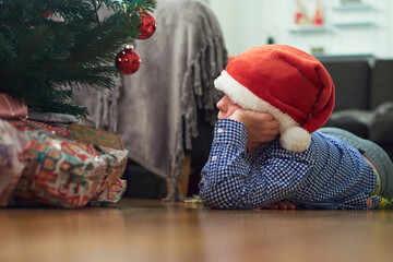 A young boy is longing to start to open Christmas gifts