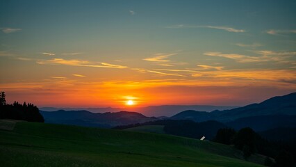 Naklejka na ściany i meble Beautiful shot of green field in mountains in the Black Forest, Germany at sunset