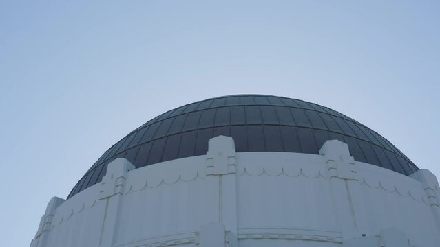 Panning shot of Griffith Observatory dome with helicopter flying in the background located in Hollywood Hills Southern California.