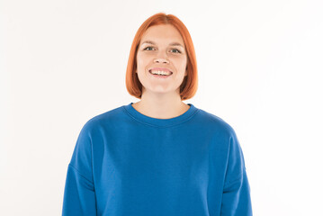 Portrait of a young redhead girl with a blue jumper on a white background.