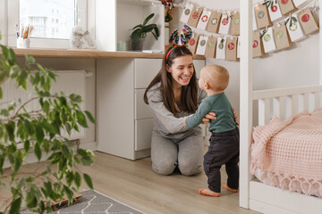 Mother with infant child having fun Christmas advent calendar tasks and gifts. Baby boy excited about festive surprise and play at home. Family celebration and preparation for New Year