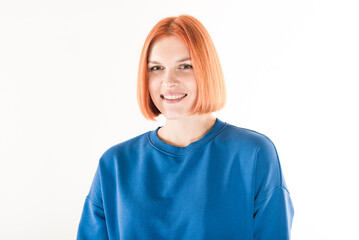 Portrait of a young redhead girl with a blue jumper on a white background.