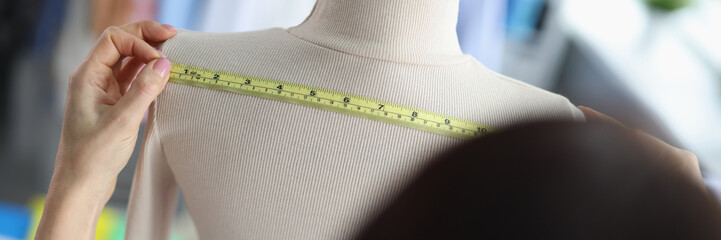 Fashion designer stylist takes measurements of clothes on mannequin