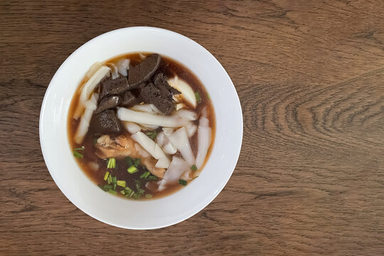Image of Kway chap ,the Asian local and popular food, consist of a noodle soup made with dark soy sauce, pork, pork blood; vegetables and hard boiled eggs on wooden  table.