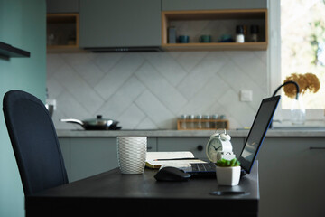Workplace with table and laptop at the kitchen. Home office and remote work concept