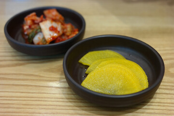 Pickled radish and kimchi are served as side dishes on a round plate.