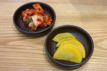 Pickled radish and kimchi are served as side dishes on a round plate.