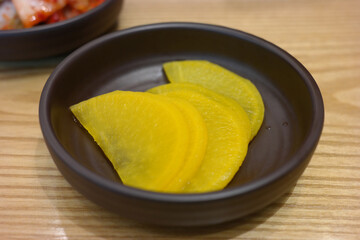 Pickled radish and kimchi are served as side dishes on a round plate.