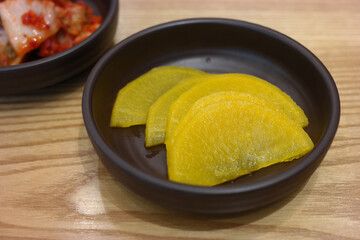 Pickled radish and kimchi are served as side dishes on a round plate.