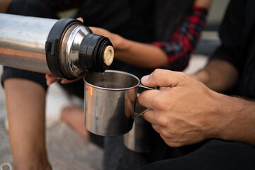 Unrecognizable traveler pouring tea to cup from thermos. Theme tourism and travel. Picnic outdoors