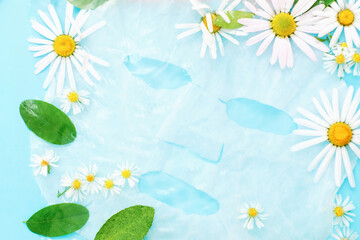Sheet mask in water with flowers on blue background, concept of natural cosmetics.
