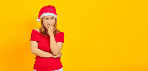 Young Asian woman wearing Christmas hat looking stressed and nervous with hand on mouth biting nails