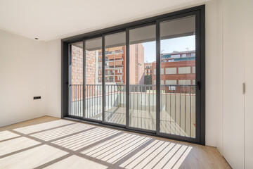 Shadows on the floor from sunlight through big windows. New room with wooden floor in a refurbished apartment.