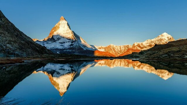 4K Time lapse of Alpenglow sunrise over Matterhorn mountain peak in Alps, Zermatt, Switzerland. Reflecting nature scene at surface of lake like in mirror. Popular travel destinatination, Europe.