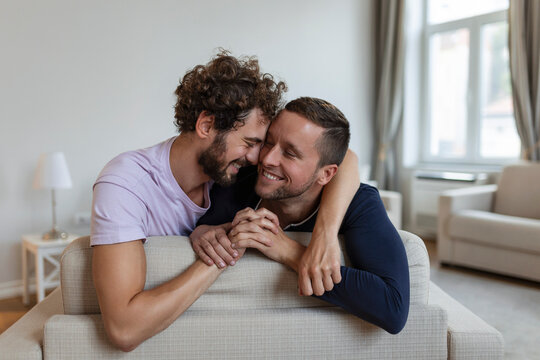 Happy gay couple lying down on the bed at home, hugging and flirting. LGBT gay couple love moments happiness concept