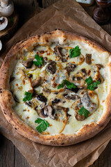 Mushroom pizza with addition mozzarella cheese and herbs on a wooden table. Vertical