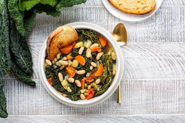 Top view of Ribollita. Tuscan bread soup made with toasted bread and vegetables. Cannellini beans,...