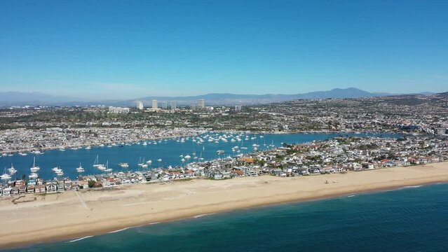 Slider Shot Aerial view of Balboa Peninsula Beach Homes, Boats, and Fashion Valley Mall in Front of Mountains