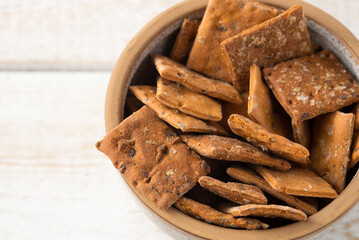 Bowl of dry crackers with tomato and basil taste on light wood background. close-up