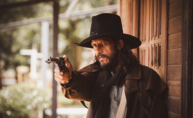 Portrait cowboy wearing in western style suite with hat posing show gun or  retro cowboy weapon is...