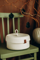 white closed craft jute basket on a green chair close-up.