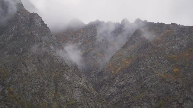 4K shot of fog around the mountain peaks during the stormy weather at Tandi in Lahaul Spiti district at Himachal Pradesh, India. Clouds rolling over the peaks of the mountain. Nature background. 
