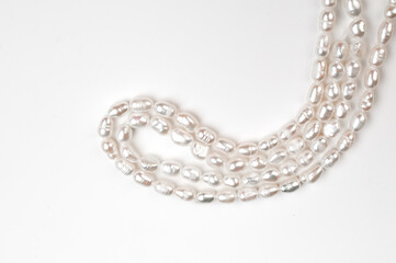 Natural freshwater round pearl beads on white background. String of pearls top view