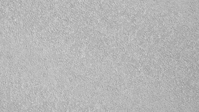 Foam plastic grainy texture of grey packaging material. Macro. Rotation. Top view