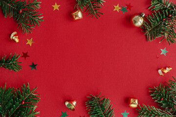 Merry Christmas and Happy Holidays!Modern christmas flat lay. Stylish christmas baubles, fir branches and confetti frame on red background. Seasons greeting card template, space for text