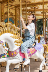 Asian girl playing on the merry-go-round at an amusement park