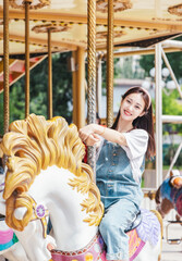 Asian girl playing on the merry-go-round at an amusement park