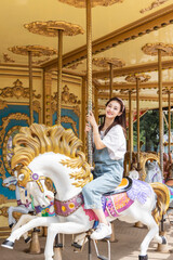 Asian girl playing on the merry-go-round at an amusement park