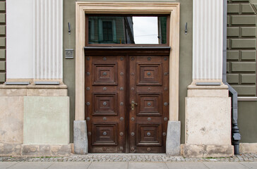 Entrance wooden double-leaf door and pilasters on the facade of the house