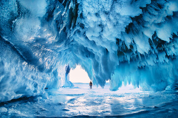 Ice cave with icicles on Baikal lake at sunset. Winter landscape of Baikal lake, Siberia, Russia