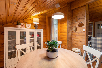 Dining room in a cozy wooden house. Rural style room with table, chairs, cupboard and decorative elements.