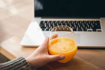 A glass of orange juice and a laptop, the concept of work and study.