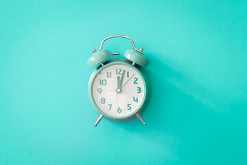 Blue alarm clock on blue background isolated, flat lay.