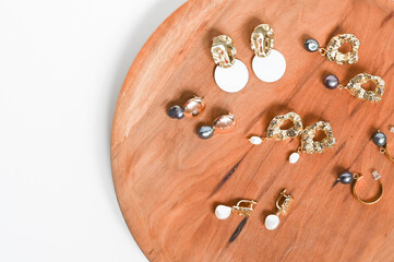 Gold earrings. Women's jewelry. Beautiful golden tones earrings with pearls on a wooden tray. Flat lay, top view