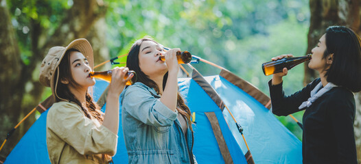 Young woman cheer and drink beverage front of camping tent