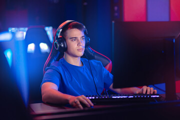 Young caucasian man pro gamer streamer playing in online video game, neon color soft focus